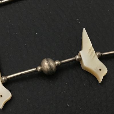 Sale Photo Thumbnail #84: Vintage Southwestern liquid silver tube bead necklace featuring carved mother-of-pearl or shell bird fetishes interspersed with silver round beads. Features a barrel screw clasp enclosure. Shows light patina and wear consistent with age.