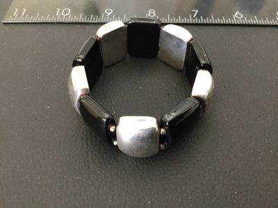 Sale Photo Thumbnail #18: Sterling silver and black onyx panel bracelet featuring alternating rectangular sterling silver segments and smooth black onyx panels on a stretch cord. Marked '925 LT THAILAND' on the back of a silver panel. Shows minor tarnishing and surface wear consis