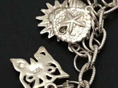 Sale Photo Thumbnail #49: A sterling silver charm bracelet featuring various celestial and aquatic/nautical themed charms including suns, butterflies, seashells, starfish, and sand dollars. Multiple charms are marked '925' for sterling silver quality. Features a lobster claw clasp