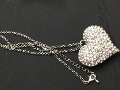 Sale Photo Thumbnail #153: A silver-tone chain necklace featuring a large heart-shaped pendant encrusted with clear and aurora borealis pave rhinestones. The back of the pendant features a openwork filigree heart pattern. Features an adjustable rolo chain with a lobster claw clasp.