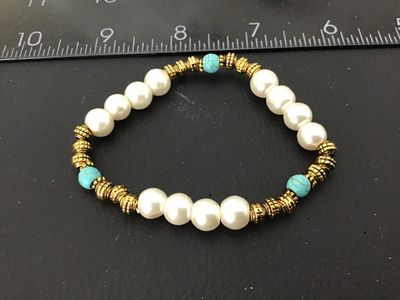 Sale Photo Thumbnail #27: Fashion stretch bracelet featuring off-white synthetic pearls, textured gold-tone spacers, and turquoise-colored accent beads. Measures approximately 2.5 inches in diameter resting. In good pre-owned condition with light wear.