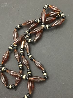 Sale Photo Thumbnail #171: Long vintage beaded strand necklace featuring amber-toned fluted/marquise acrylic beads alternating with black round beads and textured gold-tone spacers. Features a threaded barrel clasp closure. Measures approximately 30+ inches in length. In good vinta