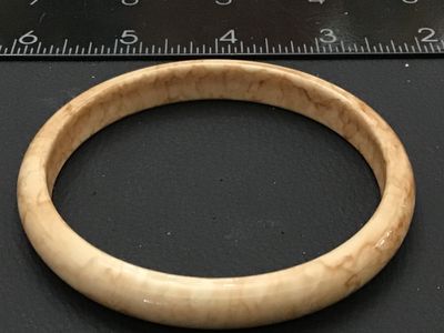 Sale Photo Thumbnail #230: A vintage solid bangle bracelet featuring a smooth, polished finish with cream and tan marbled or swirling tones, characteristic of faux tortoiseshell, celluloid, or resin/bakelite style jewelry. Measures approximately 2.5 inches in inner diameter based o