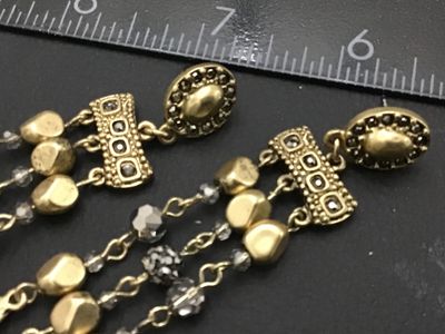 Sale Photo Thumbnail #277: Pair of ornate gold-tone dangle earrings featuring multi-strand drop chains with faceted dark crystal beads and hammered teardrop charms. Pierced post backings. Measure approximately 2.5 to 3 inches long. Good condition with no missing beads or visible da