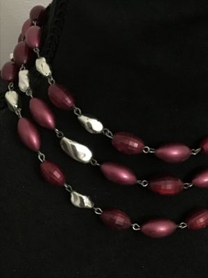 Sale Photo Thumbnail #174: A vintage multi-strand costume necklace featuring burgundy faceted and smooth oval beads interspersed with silver-tone freeform accents. Secured with an adjustable shepherd's hook clasp and decorative filigree end piece. Appears to be in good vintage cond