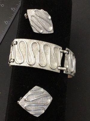 Sale Photo Thumbnail #188: Vintage Sarah Coventry silver-tone costume jewelry set featuring a panel link bracelet and matching diamond-shaped clip-on earrings with a textured surface and raised swirl design. The bracelet measures approximately 7.25 inches long. Signed 'SARAH COV' o