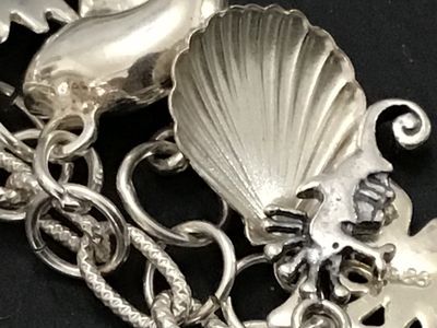 Sale Photo Thumbnail #51: A sterling silver charm bracelet featuring various celestial and aquatic/nautical themed charms including suns, butterflies, seashells, starfish, and sand dollars. Multiple charms are marked '925' for sterling silver quality. Features a lobster claw clasp