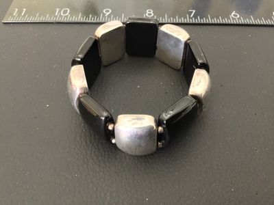Sale Photo Thumbnail #19: Sterling silver and black onyx panel bracelet featuring alternating rectangular sterling silver segments and smooth black onyx panels on a stretch cord. Marked '925 LT THAILAND' on the back of a silver panel. Shows minor tarnishing and surface wear consis