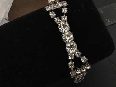 Sale Photo Thumbnail #37: Vintage silver-tone costume jewelry bracelet featuring a double strand of prong-set clear sparkling rhinestones with a central focal accent of larger round rhinestones. Features a fold-over clasp closure. Measures approximately 7 inches in length. In good