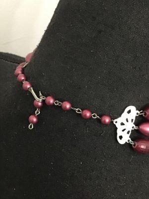 Sale Photo Thumbnail #175: A vintage multi-strand costume necklace featuring burgundy faceted and smooth oval beads interspersed with silver-tone freeform accents. Secured with an adjustable shepherd's hook clasp and decorative filigree end piece. Appears to be in good vintage cond