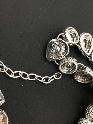 Sale Photo Thumbnail #187: A silver-tone costume jewelry necklace by Napier featuring alternating round and teardrop-shaped bezel-set rhinestones in shades of champagne and smoky purple/grey with textured border detailing. Includes an extender chain for adjustable length. Marked 'N