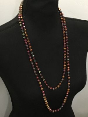 Sale Photo Thumbnail #194: Long, double-strand or flapper-length beaded necklace featuring faceted iridescent crystal glass beads in tones of copper, bronze, purple, and green. Hand-knotted or strung on thread. Shown styled on a jewelry display torso. Overall good condition with no