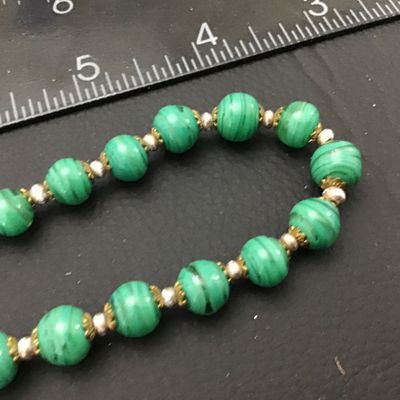 Sale Photo Thumbnail #63: Vintage beaded necklace featuring green striped art glass beads accented with brass filigree caps and small spacer beads. Measures approximately 22 inches end-to-end. Features a brass barrel screw clasp. Good vintage condition with light wear to metal acc
