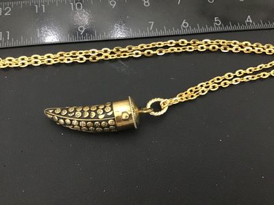 Sale Photo Thumbnail #46: A vintage gold-tone chain necklace featuring a horn-shaped pendant with detailed brass floral and stud inlays set in a dark background, capped in polished brass with twisted wire detail. The pendant measures approximately 1.5 to 2 inches long. Good vintag