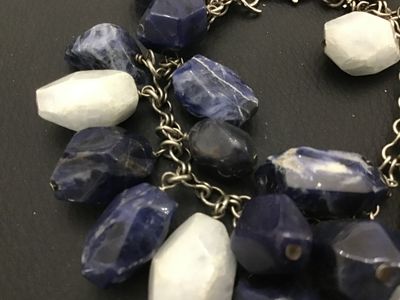 Sale Photo Thumbnail #145: A striking  925 chunky charm-style bracelet featuring large, faceted natural stone beads in shades of deep blue sodalite and white quartz or moonstone. The stones are attached to a silver-tone chain with a lobster claw clasp. The clasp appears to have fai