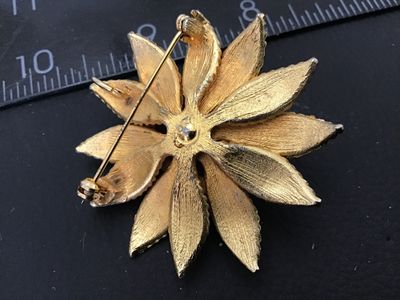 Sale Photo Thumbnail #3: A vintage gold-tone flower-shaped brooch featured with a raised domed center set with turquoise blue and faux pearl cabochons. The petals feature a textured gold finish with accenting pearls and blue beads. Measures approximately 2 inches in diameter. The