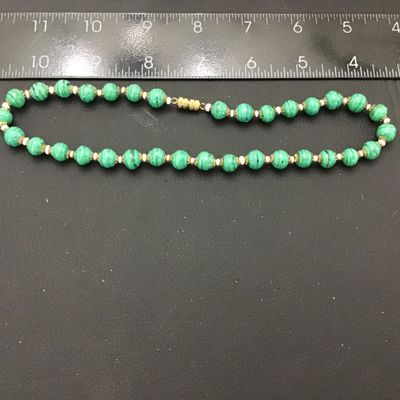 Sale Photo Thumbnail #64: Vintage beaded necklace featuring green striped art glass beads accented with brass filigree caps and small spacer beads. Measures approximately 22 inches end-to-end. Features a brass barrel screw clasp. Good vintage condition with light wear to metal acc