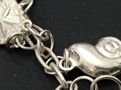Sale Photo Thumbnail #56: A sterling silver charm bracelet featuring various celestial and aquatic/nautical themed charms including suns, butterflies, seashells, starfish, and sand dollars. Multiple charms are marked '925' for sterling silver quality. Features a lobster claw clasp