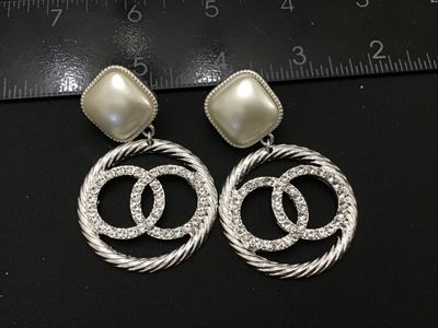 Sale Photo Thumbnail #241: Pair of statement dangle earrings in the style of a designer double-C logo. Features top square faux pearls set in textured silver-tone frames with dangling rope-textured hoops containing rhinestone-set interlocking circles. Silver-tone post backs. Measur