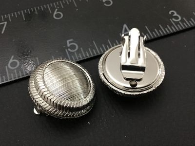 Sale Photo Thumbnail #245: Pair of vintage silver-tone clip-on earrings featuring a textured dome center and chevron patterned outer rim. Each clip-on earring measures approximately 1 inch in diameter. In good condition with functional clip backs and light vintage wear.