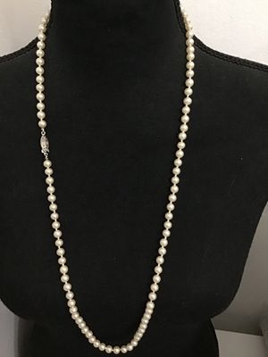 Sale Photo Thumbnail #140: A classic single strand faux or cultured pearl style necklace featuring hand-knotted construction between round cream-colored beads. Finished with a decorative silver-tone filigree marquise fishhook clasp. Overall good condition with minor vintage wear vi