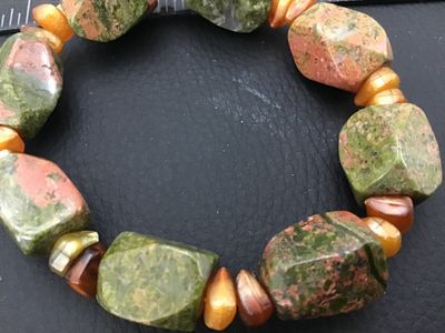 Sale Photo Thumbnail #42: A stretch beaded bracelet featuring large, faceted chunky unakite stone beads in green and pink hues, accented with smaller golden and amber-colored accent beads. Appears in good pre-owned condition with natural gemstone variations.