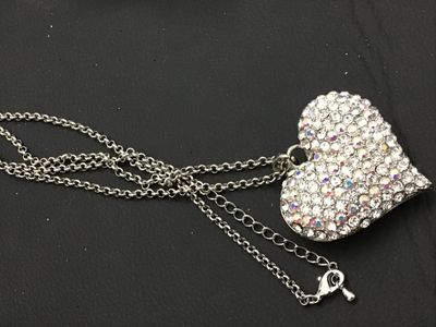 Sale Photo Thumbnail #155: A silver-tone chain necklace featuring a large heart-shaped pendant encrusted with clear and aurora borealis pave rhinestones. The back of the pendant features a openwork filigree heart pattern. Features an adjustable rolo chain with a lobster claw clasp.