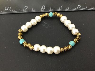 Sale Photo Thumbnail #28: Fashion stretch bracelet featuring off-white synthetic pearls, textured gold-tone spacers, and turquoise-colored accent beads. Measures approximately 2.5 inches in diameter resting. In good pre-owned condition with light wear.