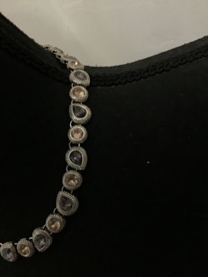 Sale Photo Thumbnail #186: A silver-tone costume jewelry necklace by Napier featuring alternating round and teardrop-shaped bezel-set rhinestones in shades of champagne and smoky purple/grey with textured border detailing. Includes an extender chain for adjustable length. Marked 'N
