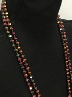 Sale Photo Thumbnail #195: Long, double-strand or flapper-length beaded necklace featuring faceted iridescent crystal glass beads in tones of copper, bronze, purple, and green. Hand-knotted or strung on thread. Shown styled on a jewelry display torso. Overall good condition with no