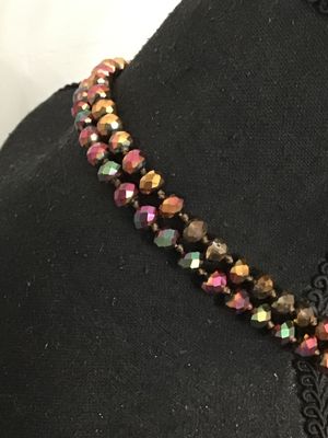 Sale Photo Thumbnail #192: Long, double-strand or flapper-length beaded necklace featuring faceted iridescent crystal glass beads in tones of copper, bronze, purple, and green. Hand-knotted or strung on thread. Shown styled on a jewelry display torso. Overall good condition with no