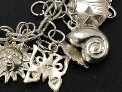 Sale Photo Thumbnail #53: A sterling silver charm bracelet featuring various celestial and aquatic/nautical themed charms including suns, butterflies, seashells, starfish, and sand dollars. Multiple charms are marked '925' for sterling silver quality. Features a lobster claw clasp