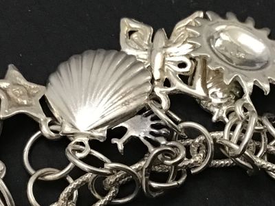 Sale Photo Thumbnail #50: A sterling silver charm bracelet featuring various celestial and aquatic/nautical themed charms including suns, butterflies, seashells, starfish, and sand dollars. Multiple charms are marked '925' for sterling silver quality. Features a lobster claw clasp