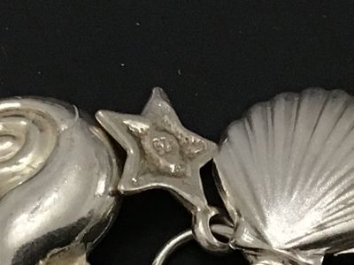 Sale Photo Thumbnail #52: A sterling silver charm bracelet featuring various celestial and aquatic/nautical themed charms including suns, butterflies, seashells, starfish, and sand dollars. Multiple charms are marked '925' for sterling silver quality. Features a lobster claw clasp