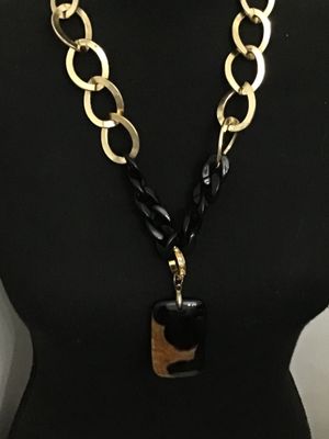 Sale Photo Thumbnail #196: Statement necklace by Traci Lynn featuring gold-tone open oval links combined with black curb links, completed with a toggle clasp closure marked TRACI LYNN. The necklace features a rectangular black and tortoise-shell style acrylic or stone pendant accen