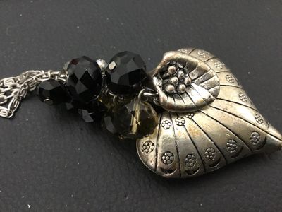 Sale Photo Thumbnail #133: Long silver-tone double-chain necklace featuring a detailed textured nautilus shell pendant clustered with faceted black and smoky glass beads. Good condition with light minor surface wear to the finish.