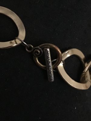 Sale Photo Thumbnail #198: Statement necklace by Traci Lynn featuring gold-tone open oval links combined with black curb links, completed with a toggle clasp closure marked TRACI LYNN. The necklace features a rectangular black and tortoise-shell style acrylic or stone pendant accen