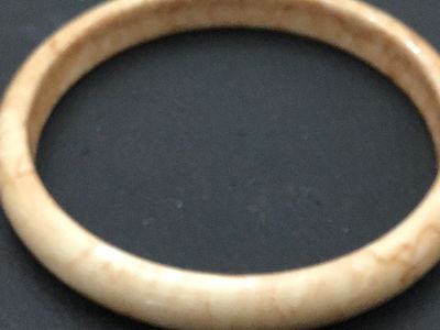 Sale Photo Thumbnail #231: A vintage solid bangle bracelet featuring a smooth, polished finish with cream and tan marbled or swirling tones, characteristic of faux tortoiseshell, celluloid, or resin/bakelite style jewelry. Measures approximately 2.5 inches in inner diameter based o