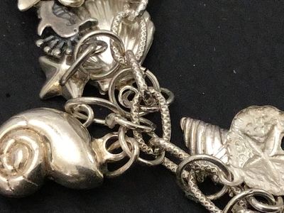 Sale Photo Thumbnail #55: A sterling silver charm bracelet featuring various celestial and aquatic/nautical themed charms including suns, butterflies, seashells, starfish, and sand dollars. Multiple charms are marked '925' for sterling silver quality. Features a lobster claw clasp