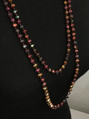 Sale Photo Thumbnail #193: Long, double-strand or flapper-length beaded necklace featuring faceted iridescent crystal glass beads in tones of copper, bronze, purple, and green. Hand-knotted or strung on thread. Shown styled on a jewelry display torso. Overall good condition with no