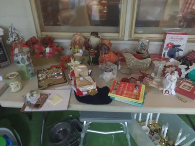Sale Photo Thumbnail #2: Folding table displaying holiday decor, books, small figurines, a decorative sleigh, and household items.