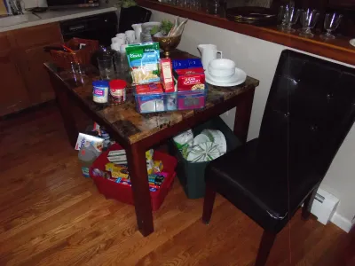 Sale Photo Thumbnail #9: Faux-marble top dining table with a black faux-leather tufted chair, displayed with kitchenware, glassware, and assorted pantry goods.