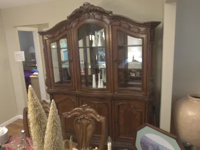 Sale Photo Thumbnail #16: Ornate French provincial style dark wood hutch featuring glass display doors, interior lighting, and carved detailing above lower storage cabinets.