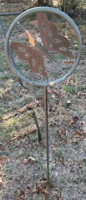 Rustic metal butterfly garden stake featuring a weathered, rusted metal butterfly silhouette inside a circular hoop mounted on a tall stake.