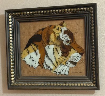 Framed vintage feather art painting depicting a tiger profile on a textured fabric backing, signed and dated 1973.