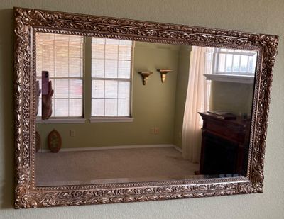 Large rectangular wall mirror featuring an ornate, carved gold-tone floral and scrollwork frame.