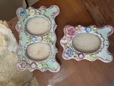 Pair of vintage ceramic picture frames with pastel glazes, applied porcelain flowers, and ornate scrollwork borders.