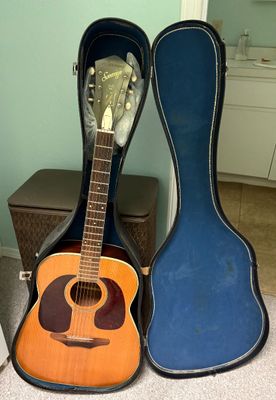 Vintage Harmony Sovereign acoustic guitar displayed inside a blue plush-lined hard shell case.