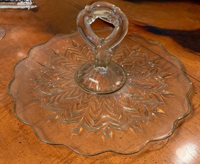 Clear pressed glass serving tray with a central loop handle and a starburst leaf pattern.