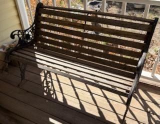 Vintage garden bench featuring ornate cast iron armrests and frame with weathered wooden slat seating.